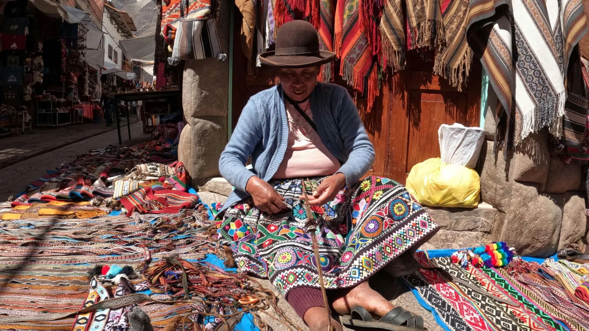 Cusco market artisan working on Andean textiles.